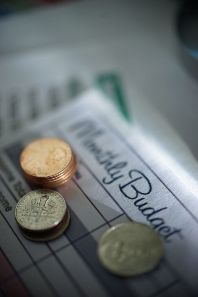 Stacks of coins on top of a monthly budget paper.