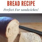 Loaf of bread with a slice cut off it. The knife is sitting next to the loaf. There is a text overlay that says 100% whole wheat bread recipe: perfect for sandwiches at the top.