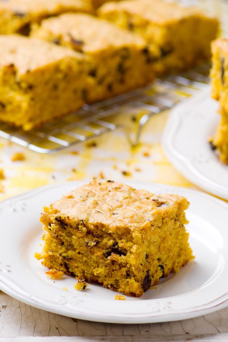 Slice of pumpkin squares recipe on a white plate with the other pieces of pumpkin bar behnd them.