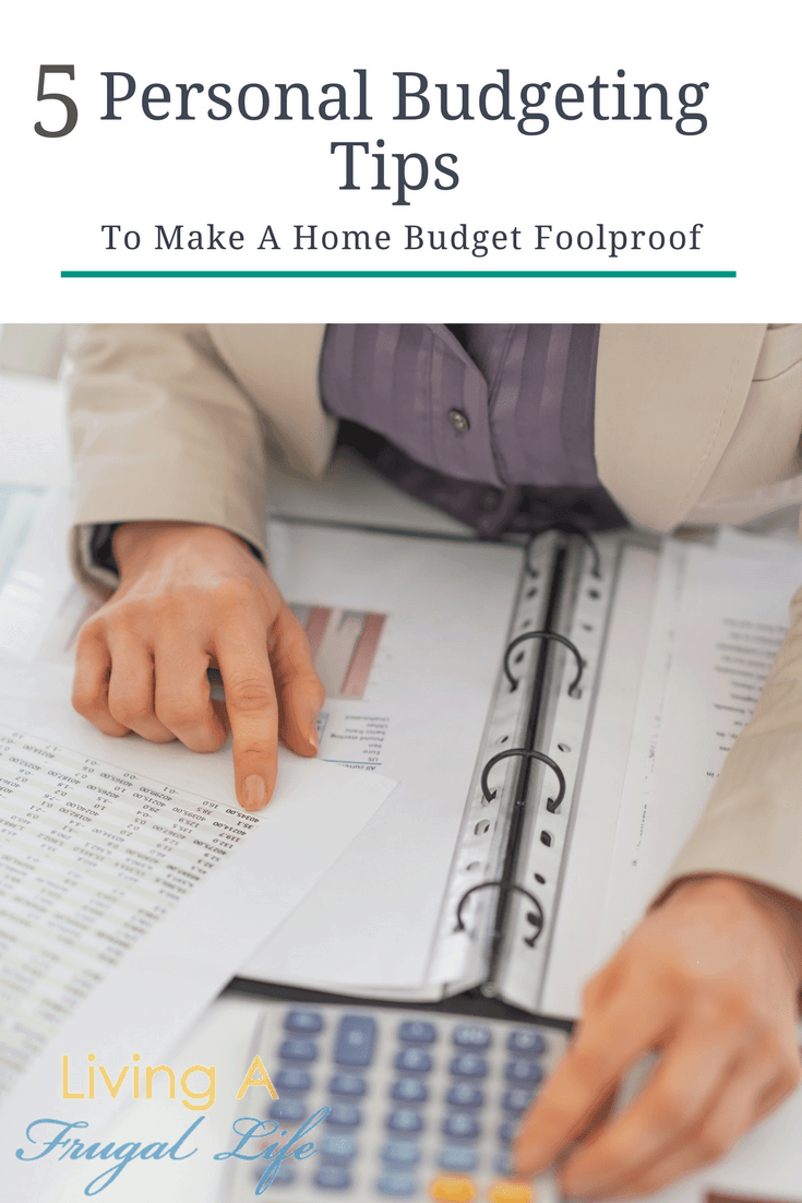 girl looking at papers with a printed budget on it. Under the paper is a binder of other financial papers and personal budgeting tips.