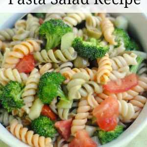 white bowl on a green background filled with tri color pasta mixed with broccoli, tomatoes, and peppers. There is a text overlay that says italian broccoli and pasta salad recipe.