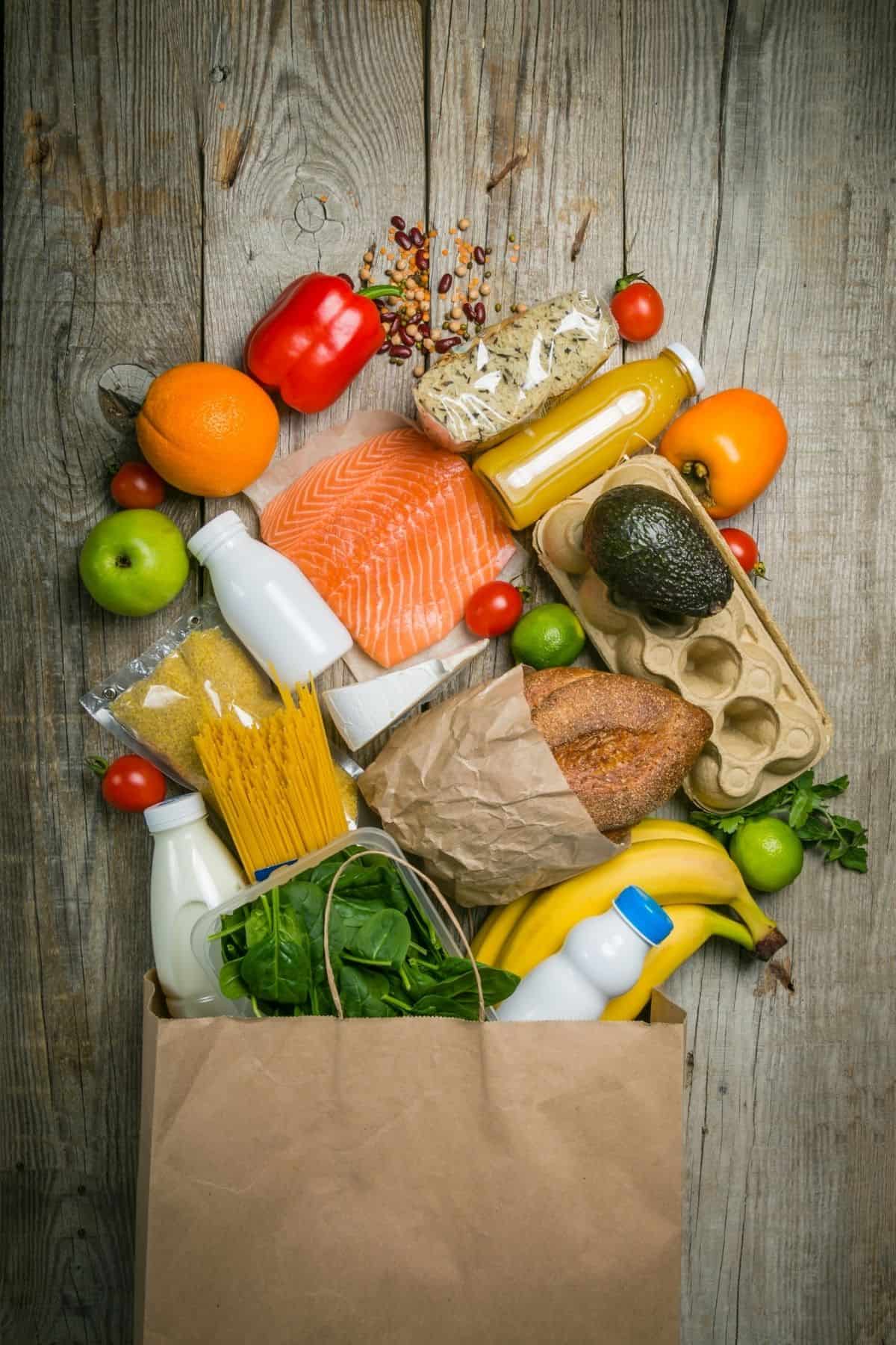 A bag of groceries laying on a table spread out.