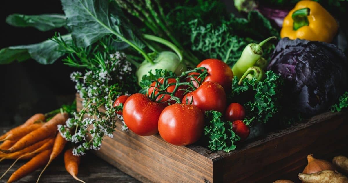 Wooden box of tomatoes, carrots, pepeprs and lettuce.