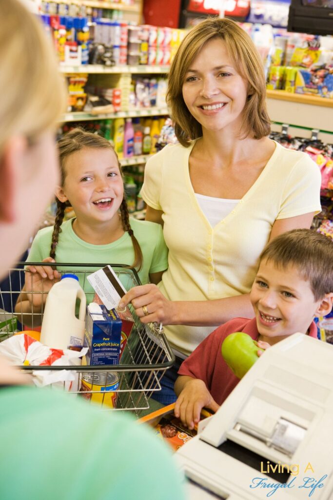 A mother and her 2 children checking out at the grocery store with coupons.