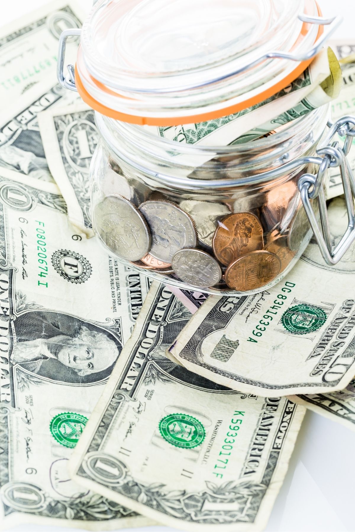 Dollar bills with a jar of coins on top