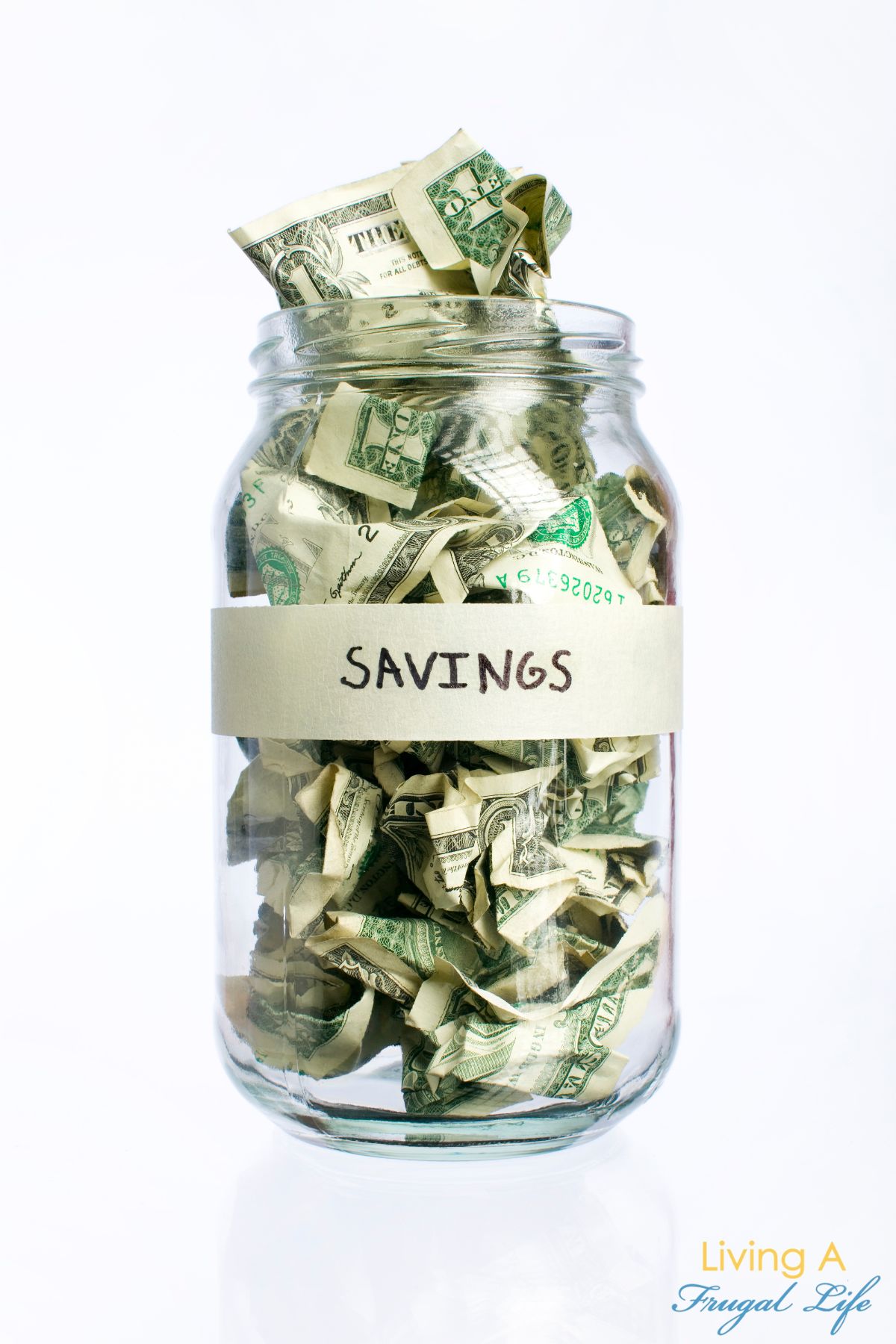 Clear jar filled with dollar bills. The word Savings is taped to the jar.