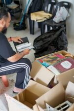 Man Sitting going through items and decluttering into a box