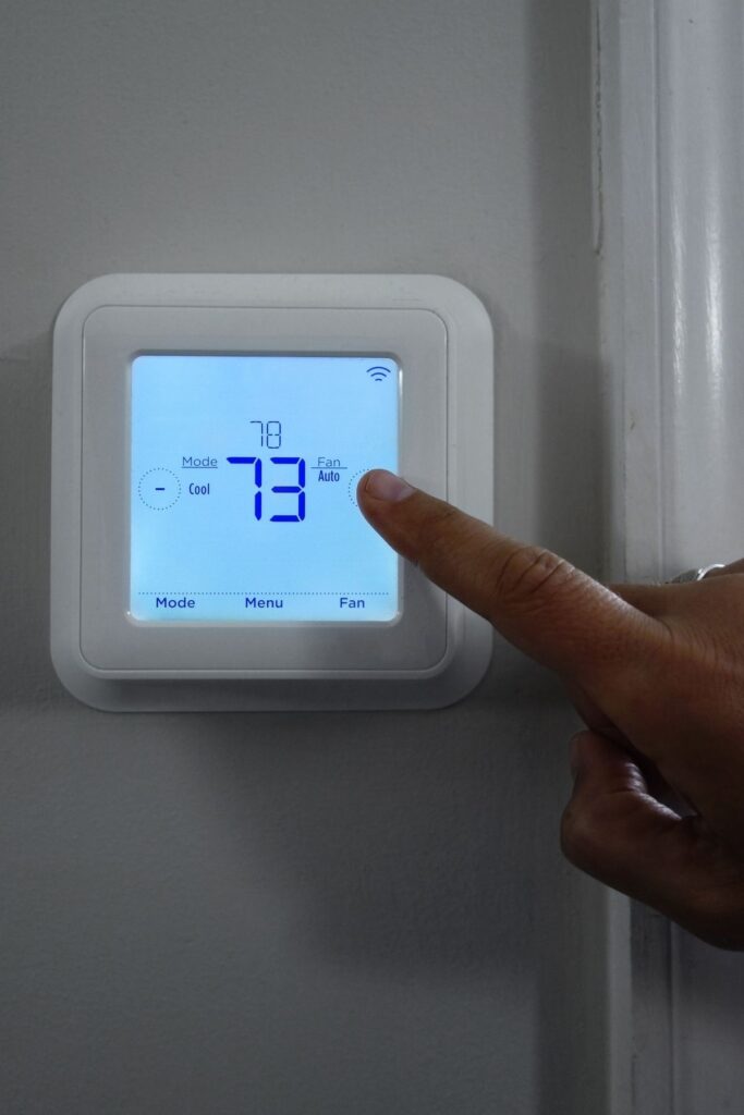 A person changing the temperature on a thermostat.